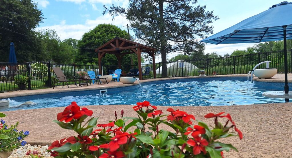 Flowers sit beside a swimming pool.