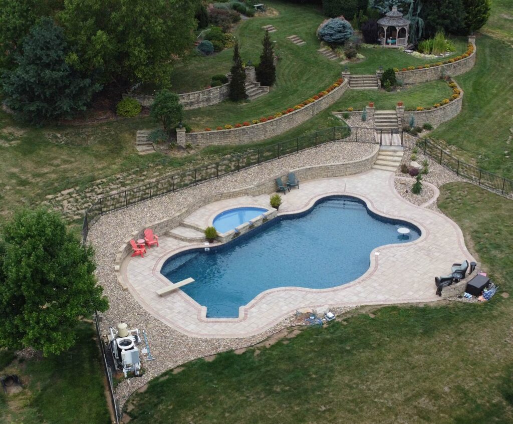 An inground swimming pool sits on a large property.