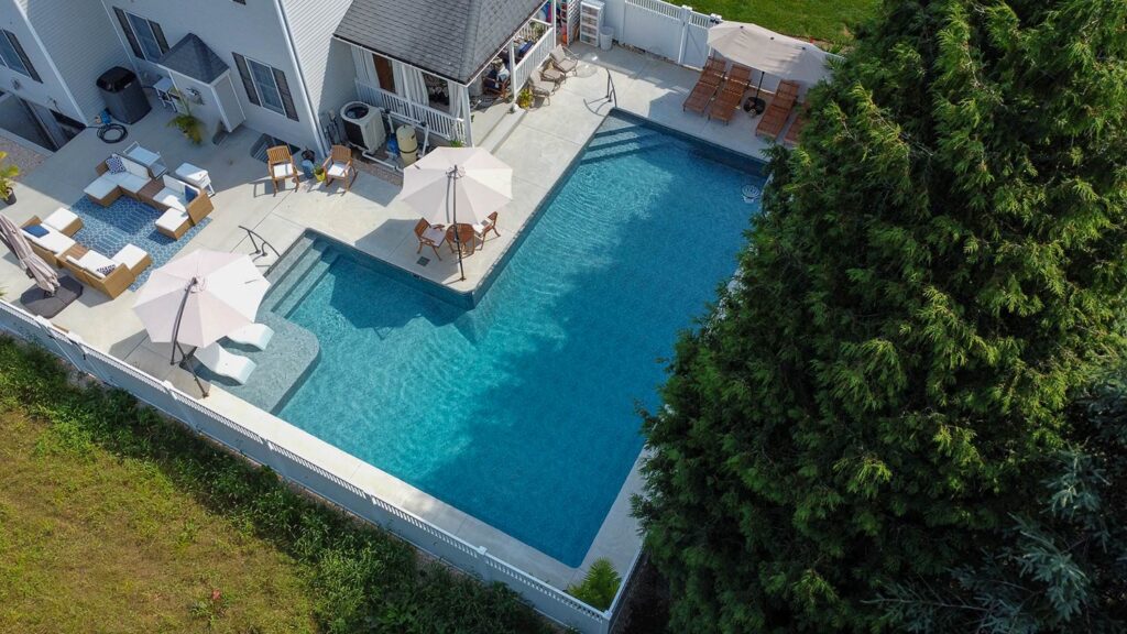 An aerial view of a large &quot;L-shaped&quot; pool with custom concrete.