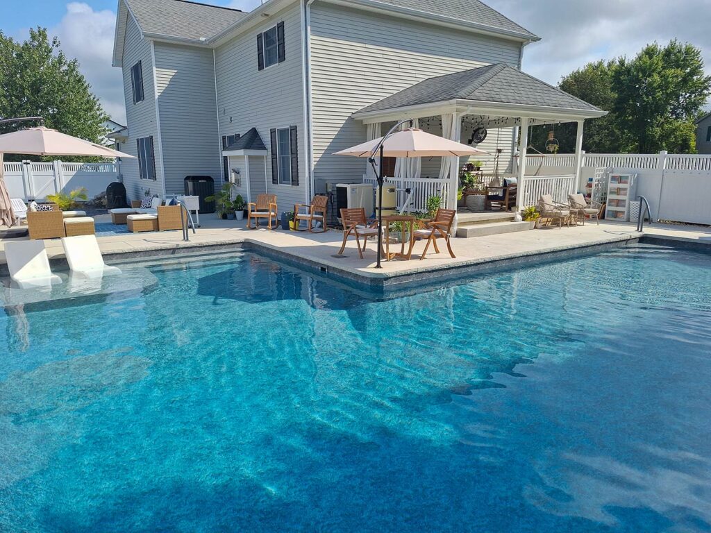 A swimming pool with patio furniture.