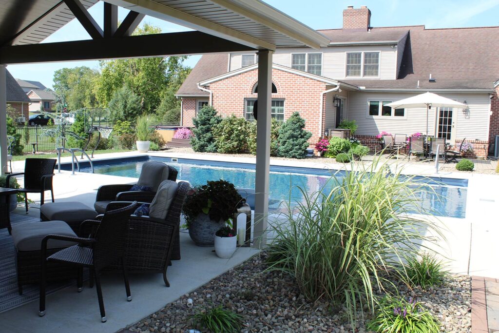 Custom landscaping and a lounge area sit beside a swimming pool.