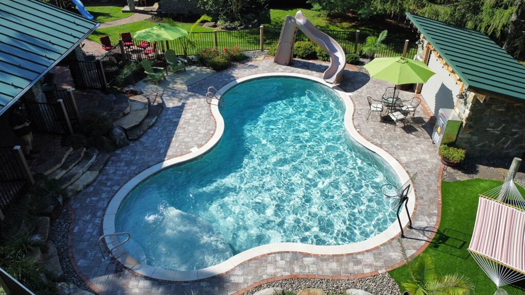 A large pool with a water slide and pool house.